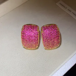 Macro view of vintage gold C-shaped earrings fully paved with pink cubic zirconia stones