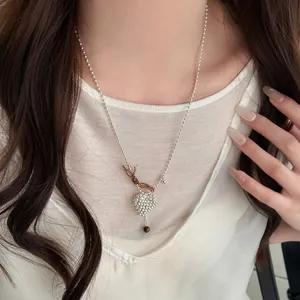 Close-up of a stylish silver beaded heart necklace worn by a female model in white