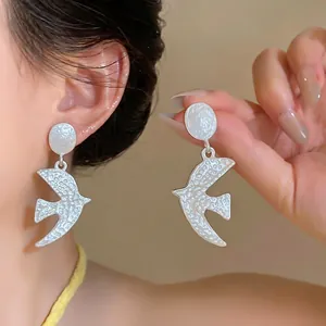 Matte silver swallow bird drop earrings featuring a unique hammered wrinkled texture