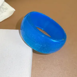 Close-up macro view of a translucent blue resin bangle with sparkling glitter interior detail