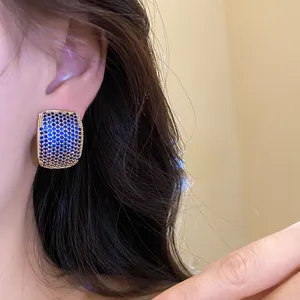 Detail view of vintage gold C-shaped earrings with blue pavé zircon stones on ear.