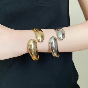 Elegant minimalist twisted teardrop open bangles in polished gold and silver finishes