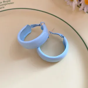 A detailed view of light blue spray-painted hoop earrings on a vintage plate.