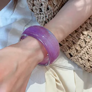 Detailed shot of a translucent purple resin bangle with shimmering glitter worn on the wrist