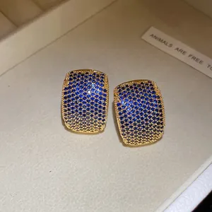 Detailed macro view of gold plated vintage C-shaped earrings with blue sparkling zircons