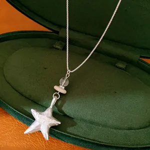 Close-up detail of silver star necklace with Promise me engraving and glass stone beads