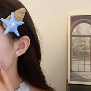 Close-up view of a blue starfish hair clip with a pearl center on a raffia fabric base