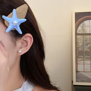 Close-up of summer style raffia hair clip with blue starfish and pearl accent