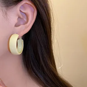 Detailed view of fresh yellow spray-painted hoop earring on model for beach style