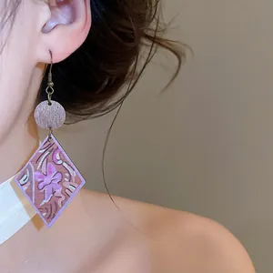 Detail view of Bohemian wooden rhombus drop earring with floral print on a model