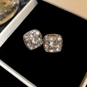 Primo piano di orecchini a lobo quadrati in argento con scintillanti pietre di zirconia