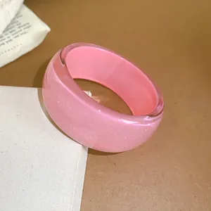 Close-up view of a pink glittery resin bangle with unique irregular geometric design