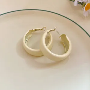 A close-up shot of cream-colored spray painted hoop earrings on a ceramic plate