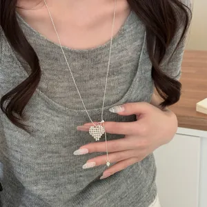 Close-up view of a silver beaded heart pendant necklace worn on a long dainty bead chain