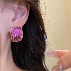 Close-up of vintage C-shaped stud earrings with sparkling pink zircons in gold frame