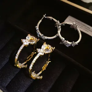 Close-up of elegant 18k gold-plated zircon butterfly hoop earrings in a black velvet box.