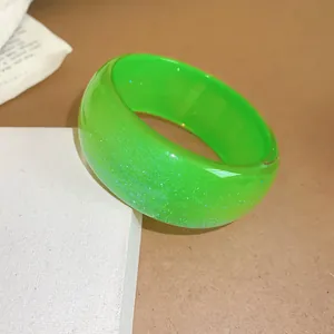 Close-up macro detail of a bright green resin bangle with a sparkling glitter finish