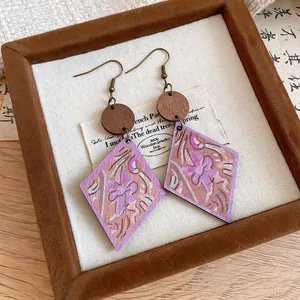 Close-up of bohemian wood earrings with purple floral print and rhombus drop