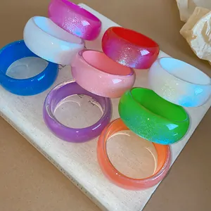 Collection of colorful irregular resin bangles with glitter on a neutral background