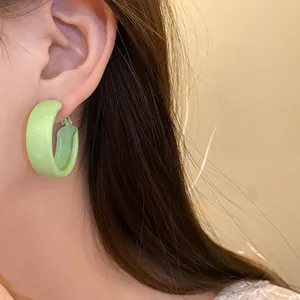 Detail view of fresh light green spray-painted hoop earrings worn on a model's ear