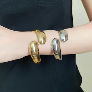 High-polished twisted water drop open bangles in gold and silver finish shown on wrist