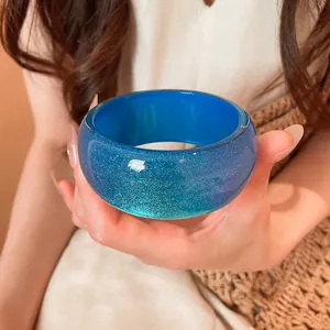 Close-up of a vibrant blue resin bangle with sparkling glitter texture and glossy finish