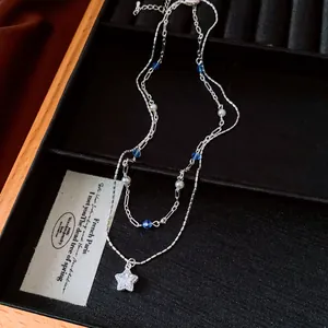 Double-layered necklace with blue beads, pearls, and a sparkling zircon star pendant