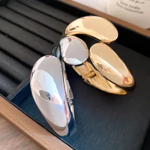 Detailed view of gold and silver twisted water drop bangles with high-polish mirror finish