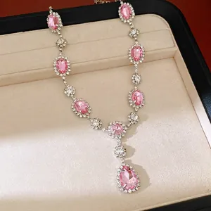 Elegant pink gemstone necklace with rhinestone teardrop pendant on a beige jewelry display tray