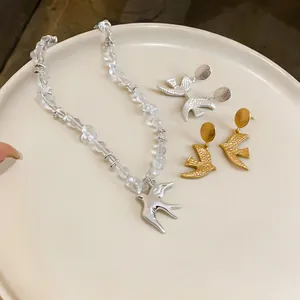Detail view of matte swallow earrings and clear beaded bird pendant necklace set