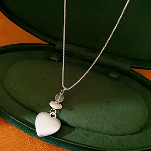 Detailed view of a silver heart pendant necklace with glass beads inside a velvet box