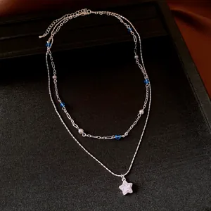Macro view of double-layered silver necklace with crystal star and blue beads
