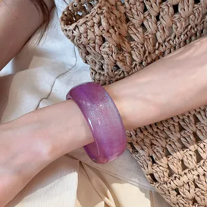 Close-up detail of a translucent purple resin bangle with sparkling glitter on a wrist