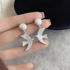 Detail view of matte silver swallow drop earrings with a hammered texture finish.