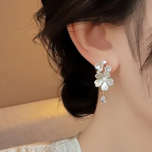Detailed macro view of elegant white flower stud earrings featuring teardrop zircon pendants
