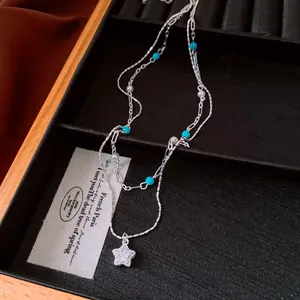 Detailed close-up of a double-layer star pendant necklace with blue beads and pearls
