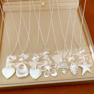 Macro detail view of silver necklaces with heart, star, and flower pendants in a tray.