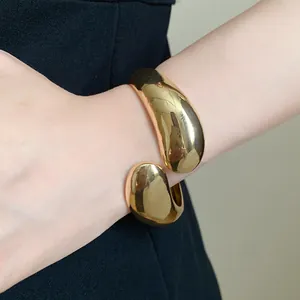 Detailed view of a shiny gold twisted teardrop cuff bracelet on a woman's wrist