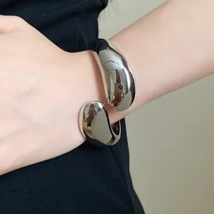 Close-up shot of a stylish silver twisted water drop open bangle on a female wrist
