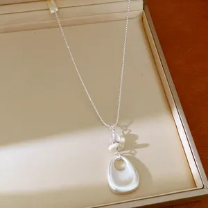 Detailed view of silver-toned necklace with teardrop pendant and stone beads