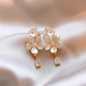 Detailed macro view of gold-toned flower earrings with teardrop zircon pendants