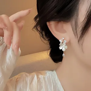 Close-up view of elegant floral drop earrings with pear-cut zircon stones on model
