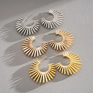 Detail of C-shaped sunburst spike earrings in silver, rose gold, and gold finishes.