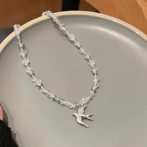 Macro view of a minimalist swallow pendant necklace with elegant clear beaded chain