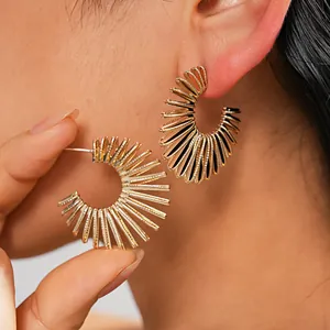 Detailed close-up of vintage style gold-tone C-shaped ribbed hoop earrings worn by a model