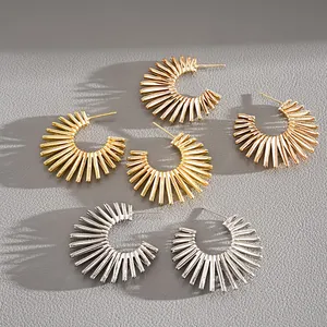 Close-up detail of vintage sunburst C-shaped metal hoop earrings in gold and silver