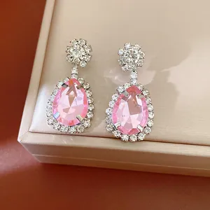 Macro view of elegant pink pear-shaped rhinestone earrings resting on a jewelry box surface