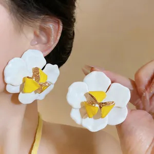 Detailansicht der übergroßen weißen Emaille-Blumenohrringe mit eleganter gelber Mitte