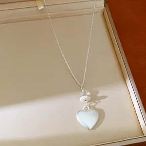 Close-up view of an elegant heart pendant necklace featuring glass stone beads and silver chain