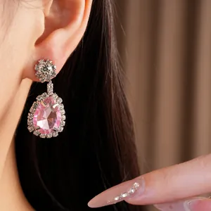 Detailed close-up showing pink pear-shaped rhinestone earrings worn on a model's ear